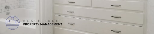 A white bathroom with a shower and a white drawer cabinet.