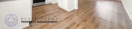 A spacious kitchen with white cabinets and a wooden floor.