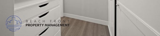 A white kitchen with a logo for Beach Front Property Management.