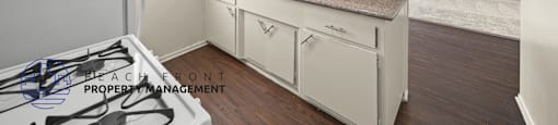 A kitchen with a stove top oven and white cabinets.