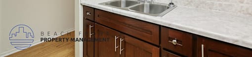 A kitchen with a white counter top and wooden cabinets.