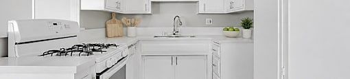 A white kitchen with a stove, sink, and refrigerator.