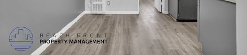 a renovated kitchen and living room with white cabinets and wood flooring