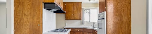 A kitchen with wooden cabinets and a stove top oven.