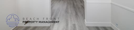 A room with a white door and a white wall with a logo of Beach Front Property Management.
