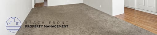A spacious room with a carpeted floor and a logo for Beach Front Property Management in the corner.