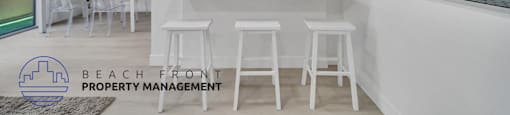 a white kitchen with a bar and white stools