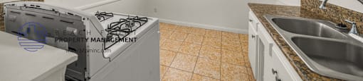 A kitchen with a stove, sink, and a fan.