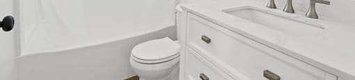 A white bathroom with a toilet, sink, and shower curtain.