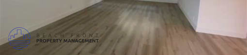 A room with wooden flooring and a window with blinds.