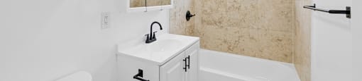 A white bathroom with a tub, sink, and mirror.