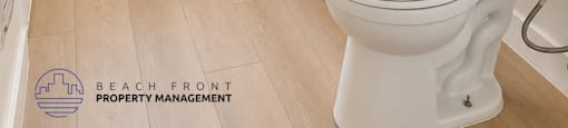 A white toilet in a bathroom with a wooden floor.