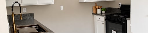 A kitchen with white cabinets and a black oven.