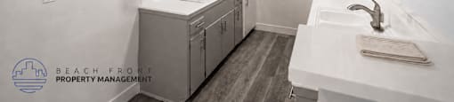 A clean, white kitchen with a sink, stove, and cabinets.
