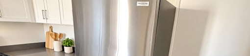 A stainless steel refrigerator in a kitchen with white cabinets.