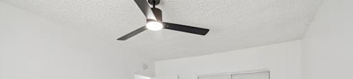 A room with a ceiling fan and wood flooring.