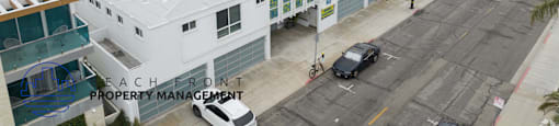 A beachfront property management company is shown in an aerial view of a coastal area with buildings and cars.