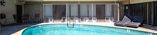 A pool in a courtyard surrounded by a building.