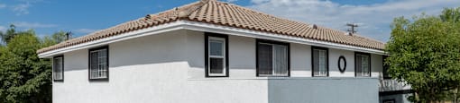 A white house with a brown roof and a car parked in front.