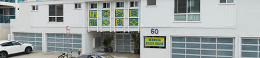A car is parked in front of a building with a sign that reads "60 Beach Blvd.".
