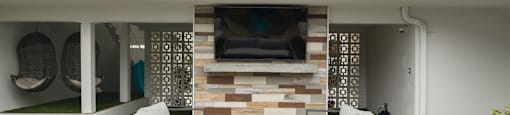 A patio with a white couch and a TV on a stand.
