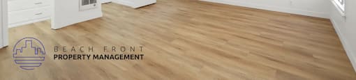 A spacious room with a ceiling fan and wooden flooring.