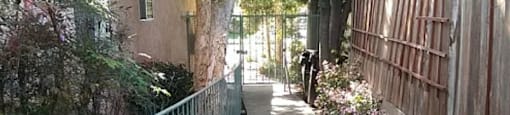 A narrow pathway with a metal railing on the left and a wooden fence on the right.
