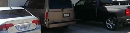 A tan station wagon is parked in front of a garage.