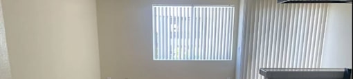 A room with wooden floors and a window with blinds.