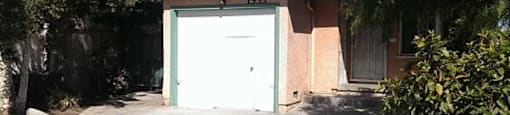 A garage with the number 1533 on it is surrounded by trees and bushes.