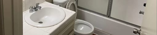 A bathroom with a sink, toilet, and shower.