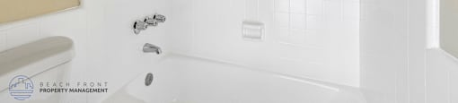 A white bathtub with a shower head and faucet.