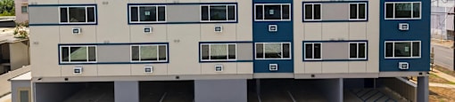 A large building with a white and blue exterior and a parking lot in front.