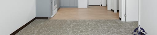 A kitchen with white cabinets and a grey floor.