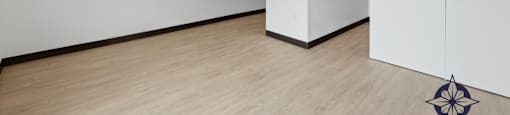 A room with a wooden floor and a white wall with a door.