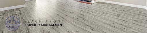 A spacious room with a fireplace and a logo for Beach Front Property Management.