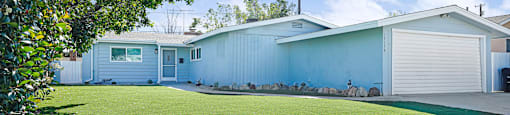 A well-maintained lawn in front of a two-story house with a garage.