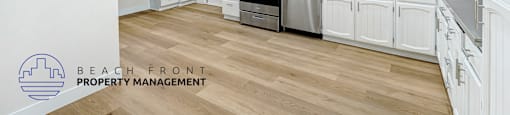 A kitchen with white cabinets and a wooden floor.