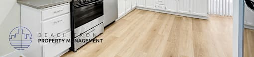 A kitchen with white cabinets and a wooden floor.