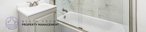 A bathroom with a marble tile wall and a glass shower stall.