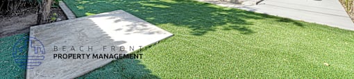 A white house with a green lawn in front of it.