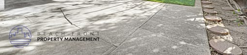 A driveway leads to a house with a sign that says "Beach Front Property Management".