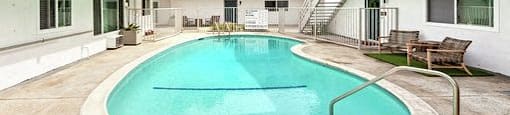 A small pool in a courtyard surrounded by white walls.