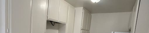 A white kitchen with a stove, sink, and cabinets.