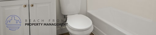 A white toilet sits next to a bathtub in a bathroom.
