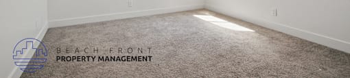 A room with a carpeted floor and two windows with blinds.