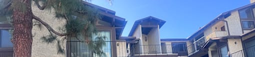A building with a balcony and a tree in front of it.