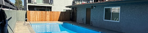 A swimming pool in a backyard with a house in the background.