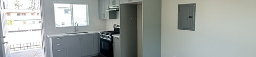 A spacious room with wooden floors and a kitchen area in the background.
