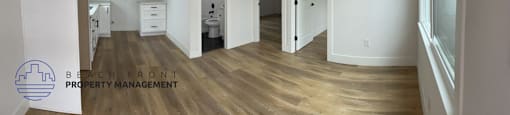 a renovated kitchen and living room with white walls and wood flooring